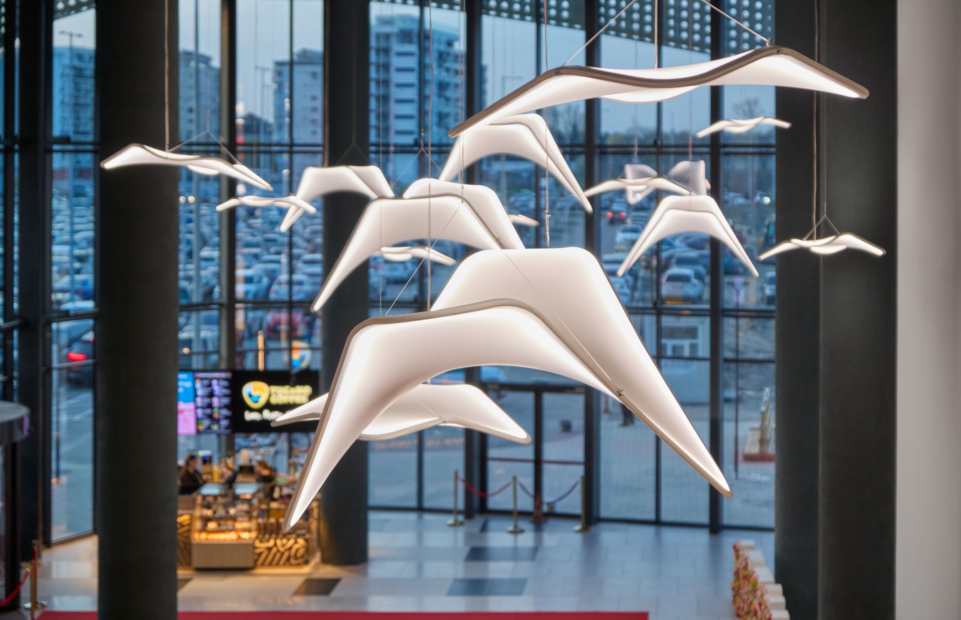 Instalație decorativă cu păsări albe suspendate lângă fațada vitrată, Arena Mall Bacău