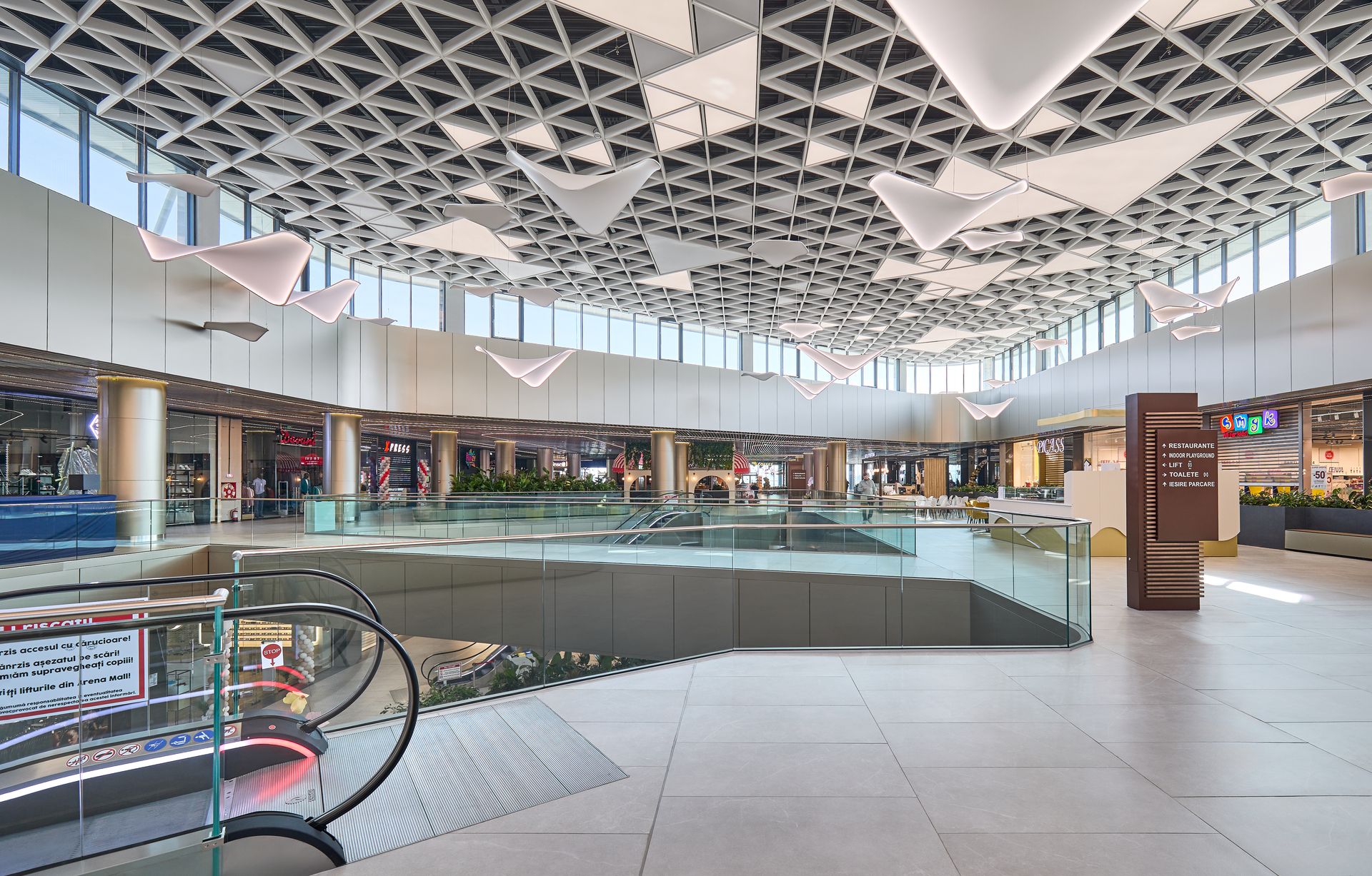 Interiorul mall-ului cu scări rulante și plafon triunghiular alb, Arena Mall Bacău